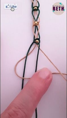 a finger is holding onto a string that has been tied together with two gold bells