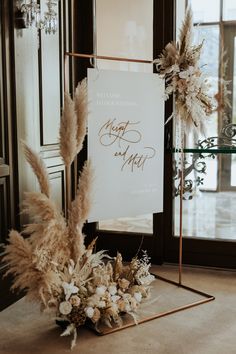 a sign that is sitting on top of a table next to some flowers and feathers