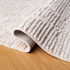 a white rug is laying on the floor next to a wooden floor with a light colored area rug