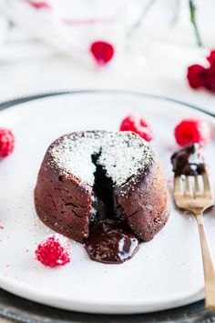 a piece of chocolate cake on a plate with raspberries