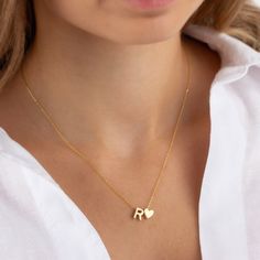 A gold heart letter necklace is a piece of jewelry that combines the shape of a heart with a letter charm. The necklace typically features a pendant in the shape of a heart, made of gold, and within the heart shape, there is a letter charm that represents a person's initial or the initial of someone they hold dear. The letter charm can be made of gold or another material, such as enamel or gemstones, and it is usually attached to the heart pendant. The necklace can be worn as a symbol of love, a Heart Letter, Letter Jewelry, Custom Initial Necklace, Necklace Initial, Letter Charm, Personalized Letters, Initial Jewelry, Birthday Jewelry Gift, Necklace Minimalist