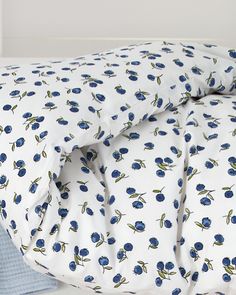 an unmade bed with blue flowers on it