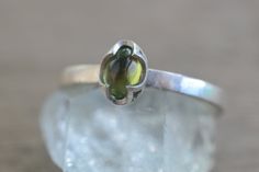 This dainty peridot ring will be made to order for you within 10 business days. It will be packaged in a little gift box along with a polishing cloth. The gemstone is a 6mm x 4mm oval peridot cabochon, a natural green stone. We've set it in a unique crown style bezel cup. The ring band is approximately 2mm wide with a smooth finish. It's entirely sterling silver, cast in recycled and reclaimed materials. We can personalise the inside of this simple peridot ring for you with engraving inside the Silver Peridot Ring, Unique Crown, Ring Bezel, Peridot Ring, Sterling Silver Jewellery, Green Crystal, Oval Stone, Green Crystals, Green Stone