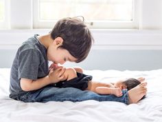 a little boy playing with his doll on the bed