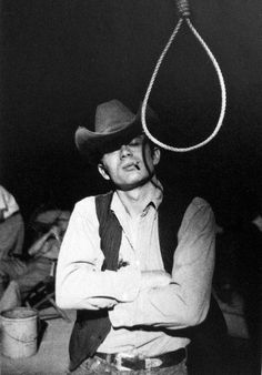 black and white photograph of a man wearing a cowboy hat with a lasso on his head