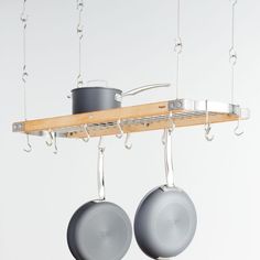 two pots and pans hanging from a wooden rack