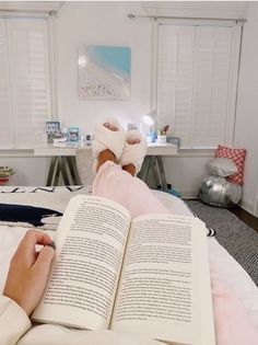 a person laying in bed with their feet up on an open book and reading it