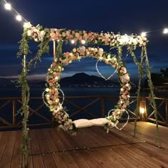 an outdoor wedding ceremony setup with flowers and lights on the deck overlooking the water at night