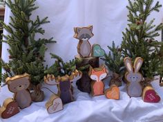 wooden cutouts of animals and trees on a white cloth covered table with pine branches