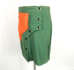 "Original new wrap over rave mini skirt from Toasta in the 1990s.  Made from 100 % polyester in mid green and orange.  The skirt is straight.   It is silky, matt and of medium weight. Features asymmetric front with 6 press studs, zipped pocket and set in pocket on one side and side pocket with zip on the other.   There were never many of these originally, and probably none now.  Made when trance ruled the world. Size S   UK   10 Flat measurements are;     Waist                   30inches / 76 cm Hips                     36 inches / 91 cm Back Length        17 inches / 43 cm Weight  205 g For collectables, curios and media visit our sister ETSY shop \" meaningoftime \".  Also check out in this shop, our 2 cutting edge clothing labels JUSTIZ and Corybant, as well as a huge selection of perfe Green Retro Cotton Mini Skirt, Fitted Green Cotton Cargo Skirt, Fitted Retro Green Mini Skirt, Green Fitted Retro Mini Skirt, Trance Party, Dance Festival, Clothing Labels, Press Studs, Side Pocket