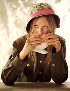 a woman wearing a hat and holding her hands to her mouth