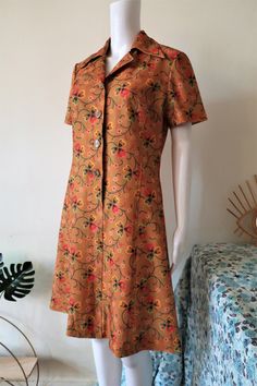 Beautiful True Vintage mini shirt dress from the late 1960s or early 1970s. Made from a soft poly fabric in a stunning shade of ochre/copper with a multicolor clover leaves pattern. Slightly fitted, short lapel collar, short sleeves, button tab. Unlined. Made in Finland! Perfect for a vacation, as the dress doesn't have to be ironed. BRAND: Finnfashion ERA: 1960s, 1970s COLOR: Ochre, green, red, black, yellow, white FABRIC: 100% polyester SIZE: Vintage size 42, fits best M (or S for a more relax Brown Vintage Dress For Spring, Retro Brown Vintage Dress For Spring, Retro Collared Dresses With Floral Print, Retro Collared Floral Print Dresses, Retro Collared Dress With Floral Print, Retro Brown Dress With Buttons, Retro Floral Print Collared Dress, 1979 Fashion, Vintage Brown Collared Dress