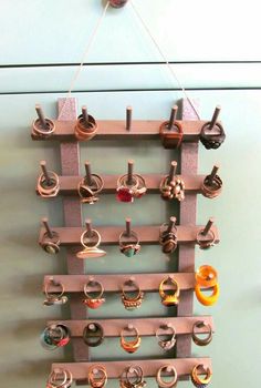 a rack with rings hanging from it's sides on a wall next to a door