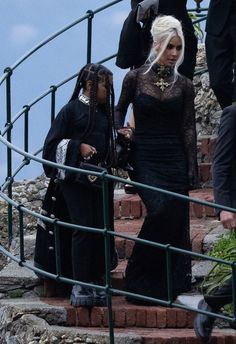 two women dressed in black walking up some stairs