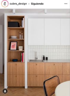 a kitchen with white walls and wooden cabinets in the center, along with a dining room table