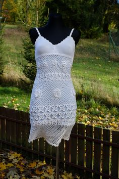 a white crochet dress on a mannequin in front of a fence