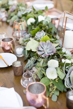 the table is set with candles, flowers and greenery for an elegant wedding reception