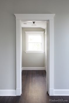 an empty room with hard wood flooring and white trim on the walls, along with a window