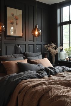 a bedroom with black walls and brown linens on the bed, two hanging lights above it