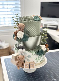 a three tiered cake decorated with flowers and teddy bears on a table next to a clock