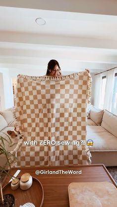 a woman sitting on top of a couch holding up a checkered blanket over her face