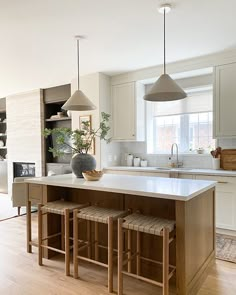 a kitchen island with stools in front of it next to an open floor plan