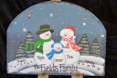 a snowman family painted on a wooden easel