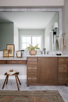 a bathroom with a large mirror, sink and wooden stool in it's center