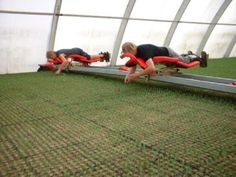 two men are working on something in a large room with green carpeted flooring