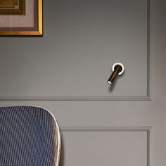 a blue chair sitting next to a gray wall with a gold framed picture on it