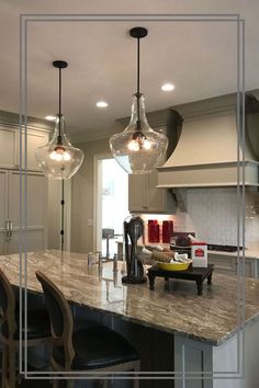 a kitchen with marble counter tops and stools in front of an island that has four lights hanging from it