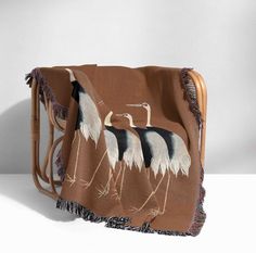 a blanket with two birds on it and fringes around the edges, sitting on a chair