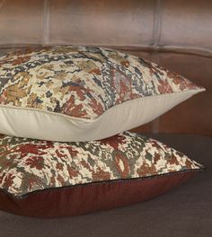 two pillows are stacked on top of each other in front of a brown headboard