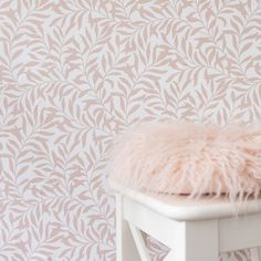 a white bench with a furry cushion on it in front of a floral wallpaper