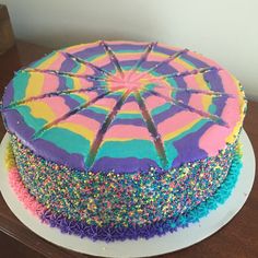 a colorful cake with sprinkles on it sitting on top of a table