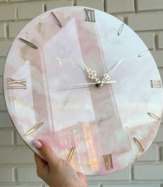 a person holding up a clock in front of a brick wall with roman numerals