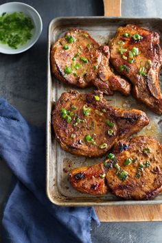 some meat is sitting on a pan with green onions