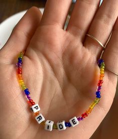 a child's hand holding a beaded bracelet with the word pride written on it