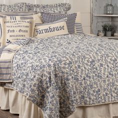 a bed with blue and white comforter, pillows and pillow cases on top of it