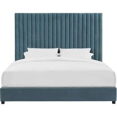 a bed with blue velvet headboard and pillows