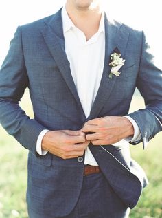 a man in a blue suit and white shirt with his hands on his lapel