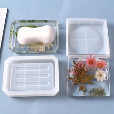 three plastic containers with flowers in them on a blue surface