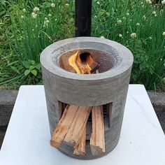 an outdoor fire pit made out of cement and wood with flames coming out of it