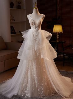 a wedding dress is displayed on a mannequin in front of a couch and lamp