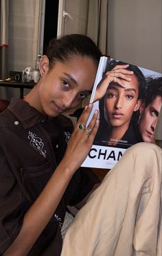 a woman sitting on a couch holding up a magazine with the cover of her hair