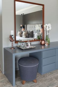 a bedroom with a vanity, mirror and stool