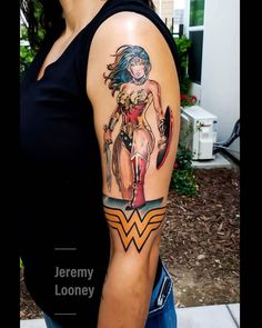 a woman with a tattoo on her arm is standing in front of a house and holding a hammer