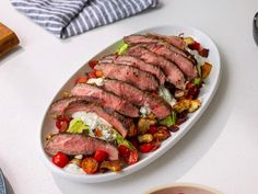 a white plate topped with sliced meat and veggies on top of a table