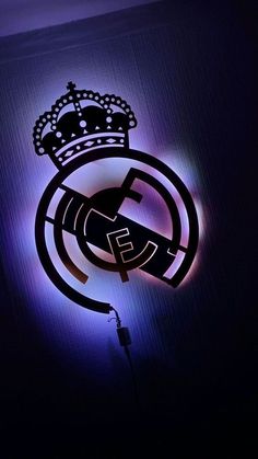 the real madrid logo is lit up in purple and blue light with a crown on top