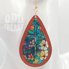 a pair of wooden earrings with stained glass and flowers in the shape of a tear